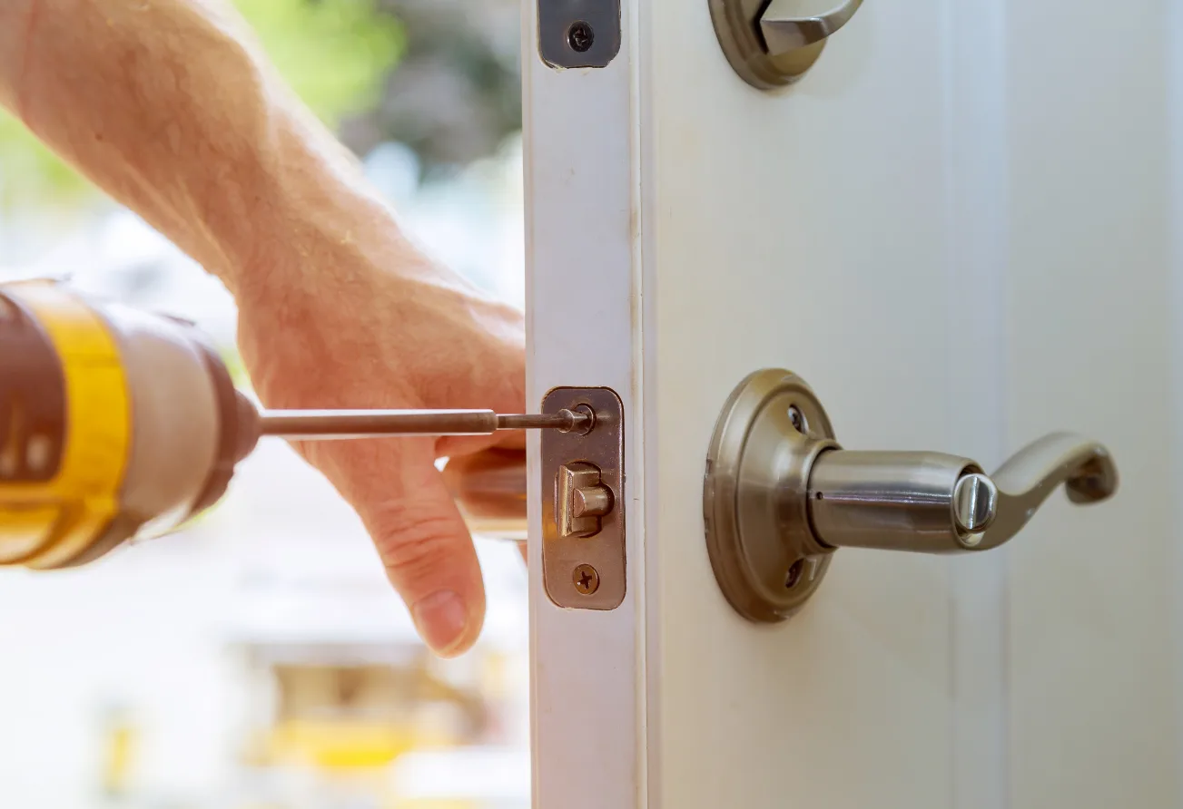 Property manager watching locksmith rekey apartment deadbolt during tenant turnover